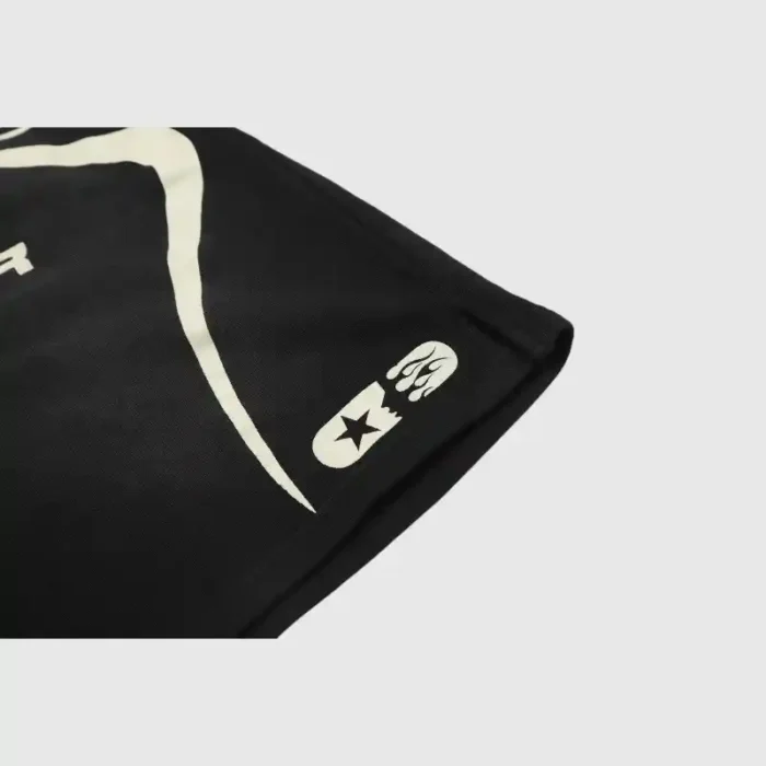 Close-up of the Hellstar Warm Up Shorts 'Black,' showcasing a stylized Hellstar design with white abstract graphics and symbols. A star and crescent moon-like shape can be seen on the lower right corner.
